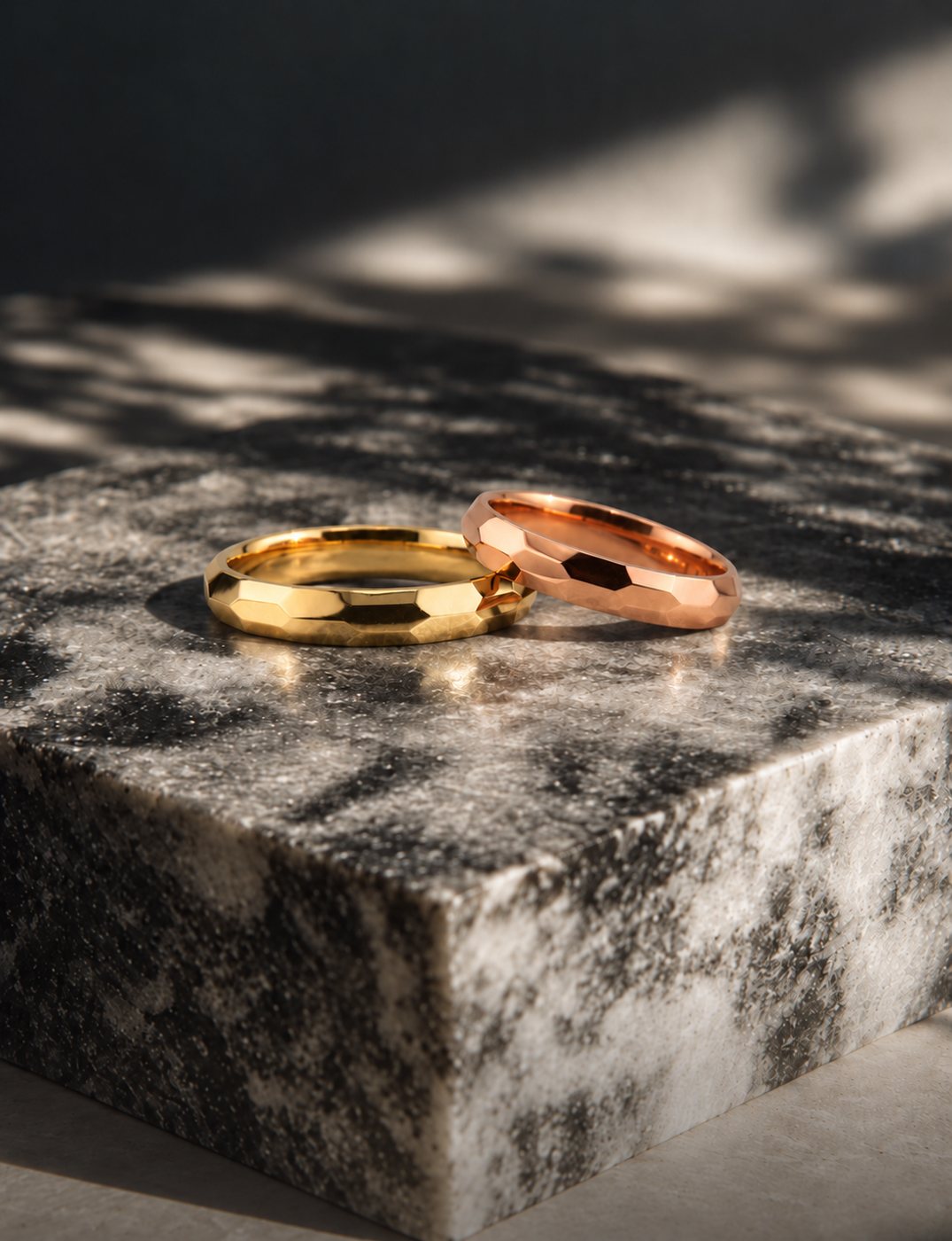 Fedi nuziali sfaccettate in oro giallo e oro rosa su marmo, Bassi Gioielli