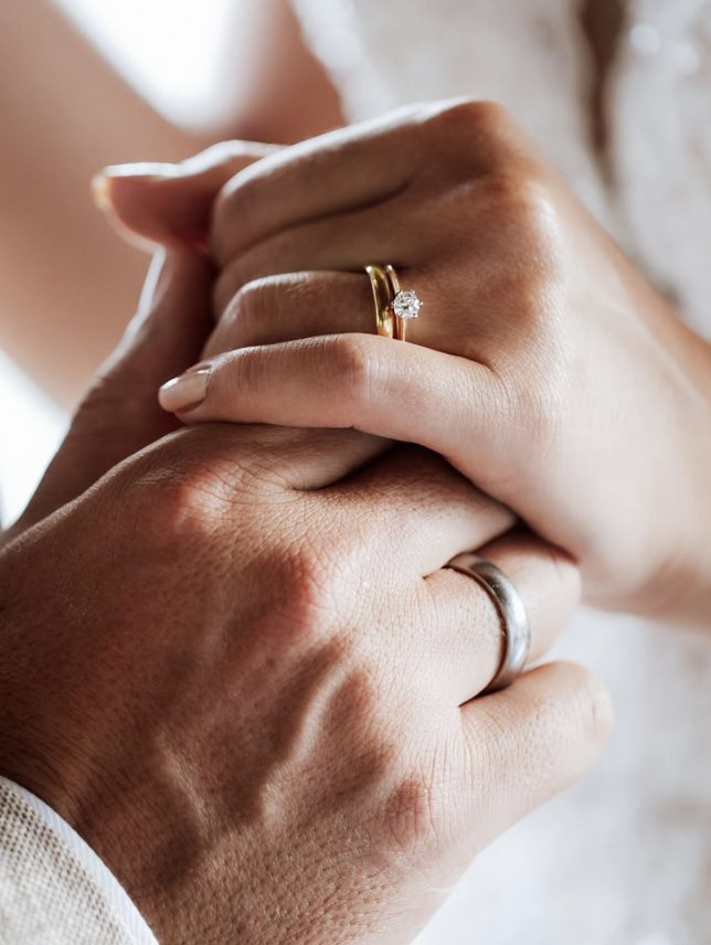 Sposi mano nella mano con fedi e solitario